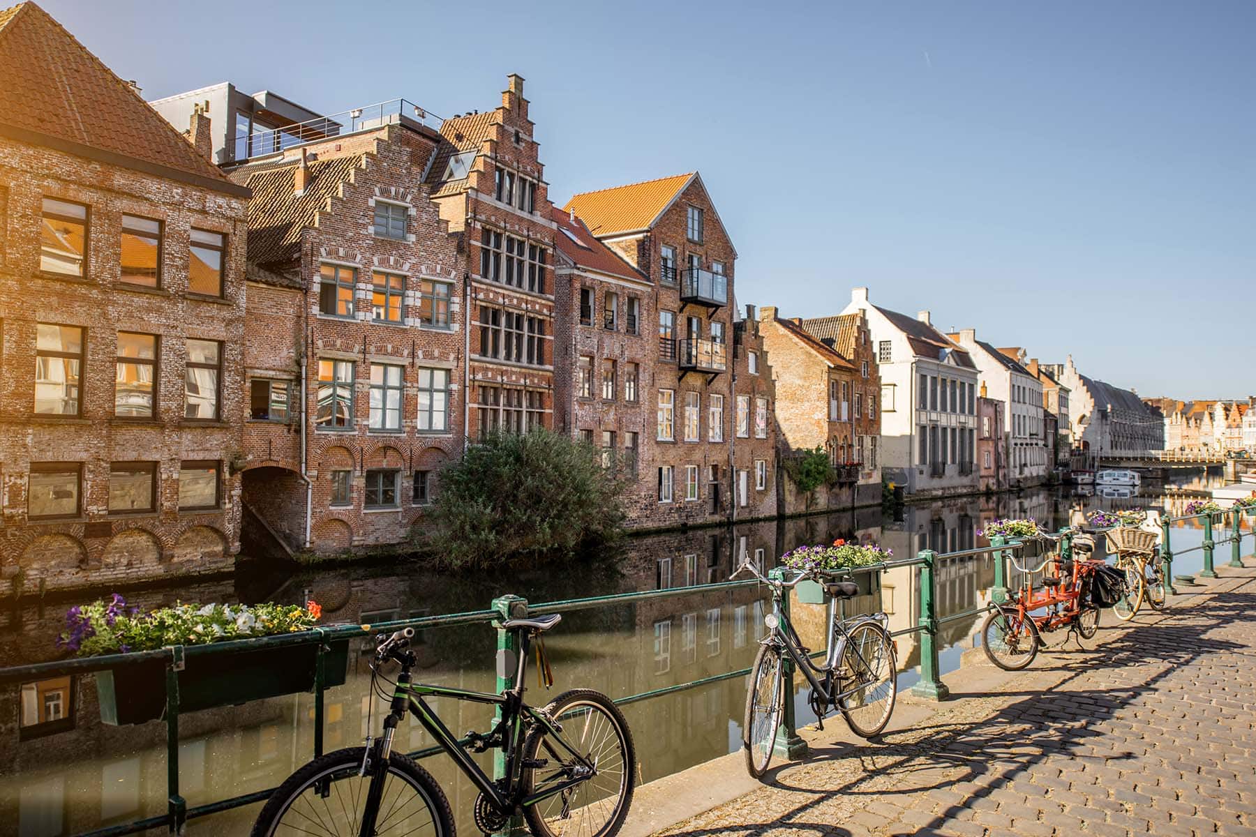 En solig bild av en kanal i Belgien med cyklar längs med staketet