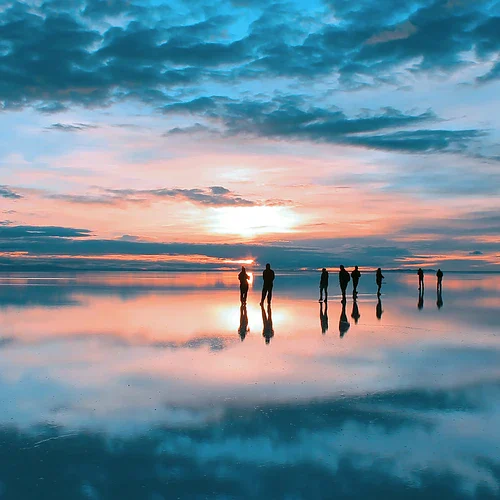 Personer som går på Salar de Uyuni i Bolivia i Sydamerika i solnedgång