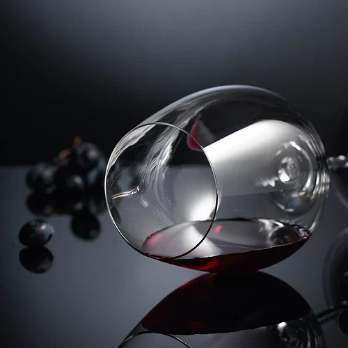 Ett glas rödvin med svarta druvor på en mörk bakgrund, elegant och inbjudande.