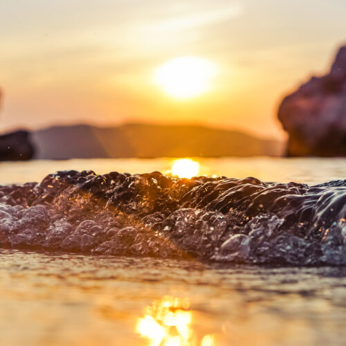 vågor på en strand i Budva i Montenegro med solnedgången i bakgrund