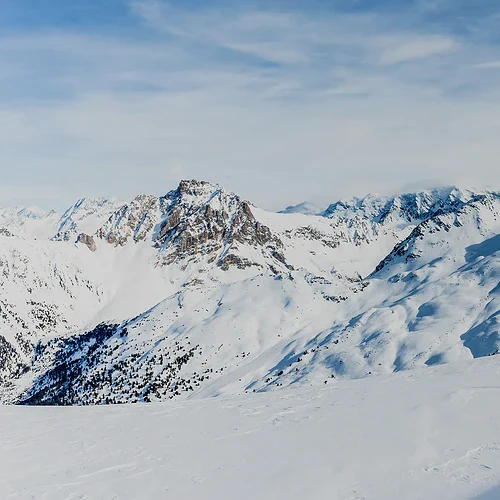 Skiåkare i snötäckta fjäll med majestätiska berg i bakgrunden, perfekt för vinteraktiviteter och skidåkning.