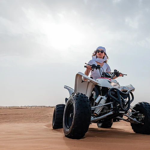 En kvinna på en 4-wheel i en öken i Dubai
