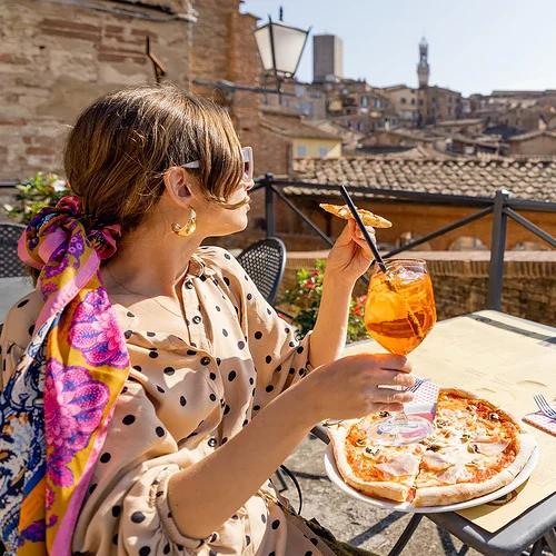 En tjej äter pizza på en takrestaurang på Elba i Italien