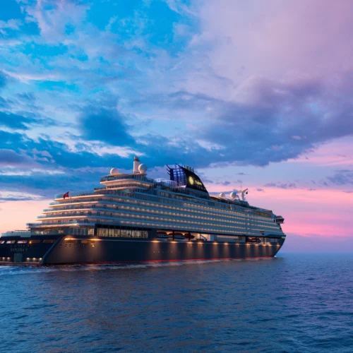 En modern lyxkryssare som seglar på havet vid solnedgången, omgiven av en färgstark himmel med blå och rosa nyanser, perfekt för exklusiva resor och avkoppling.