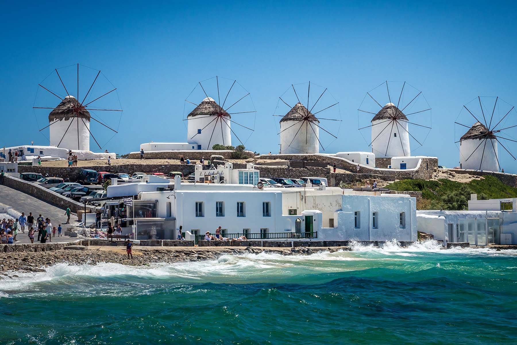 väderkvarnar på en kulle bak en by vid havet på Mykonos 