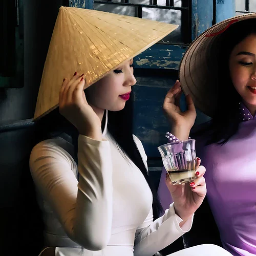 Två vietnamesiska tjejer dricker te och ler tillsammans
