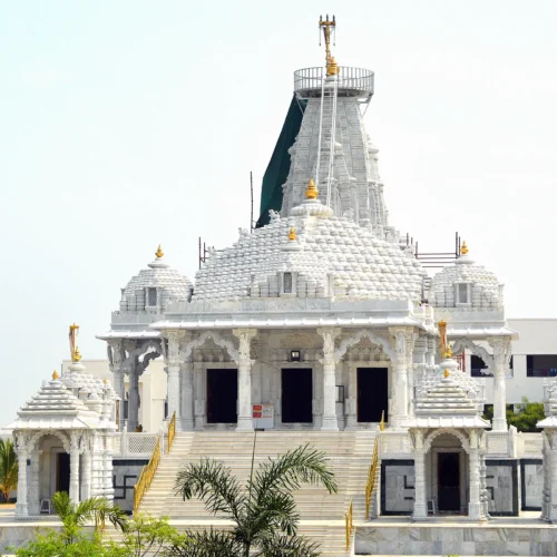 Ett vitt tempel i Chennai med palmer i front