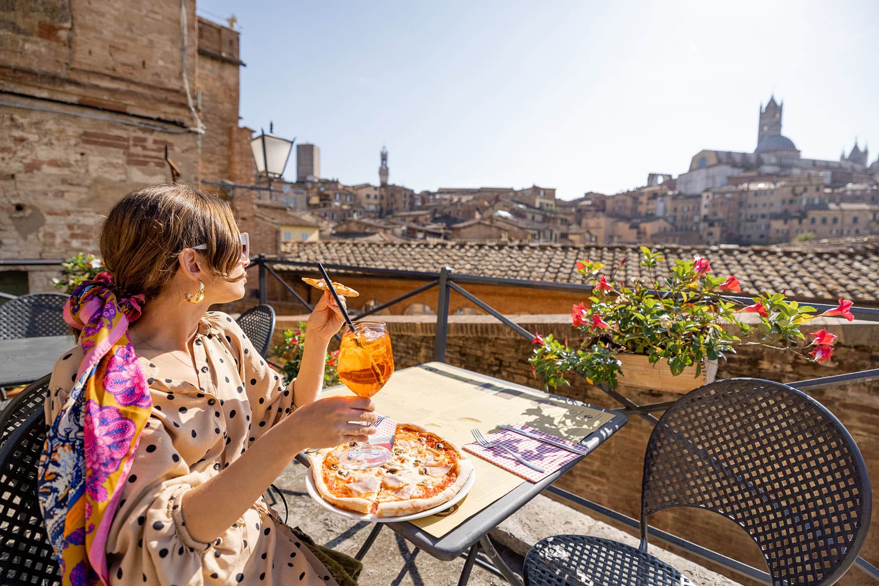 en kvinna på en roof top restaurant i Italien som äter en pizza