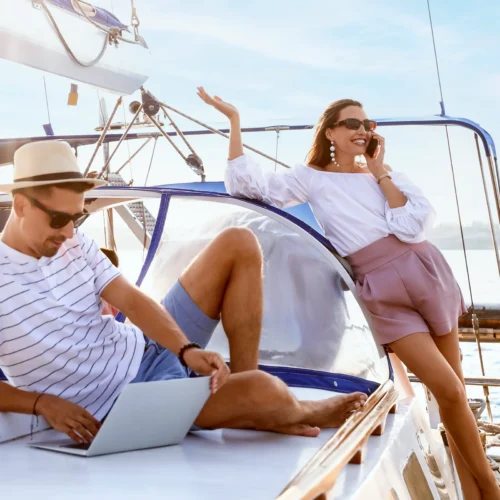Ett par på en yacht och kvinnan pratar i telefon på däck