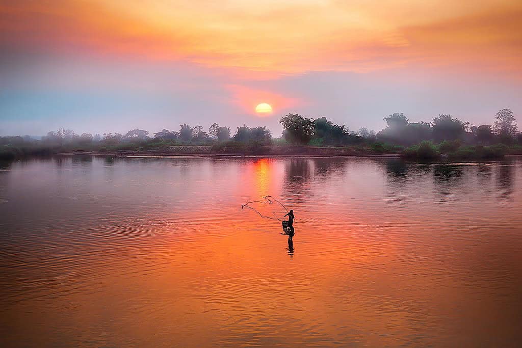 fiskare i solnedgången på en sjö i Laos
