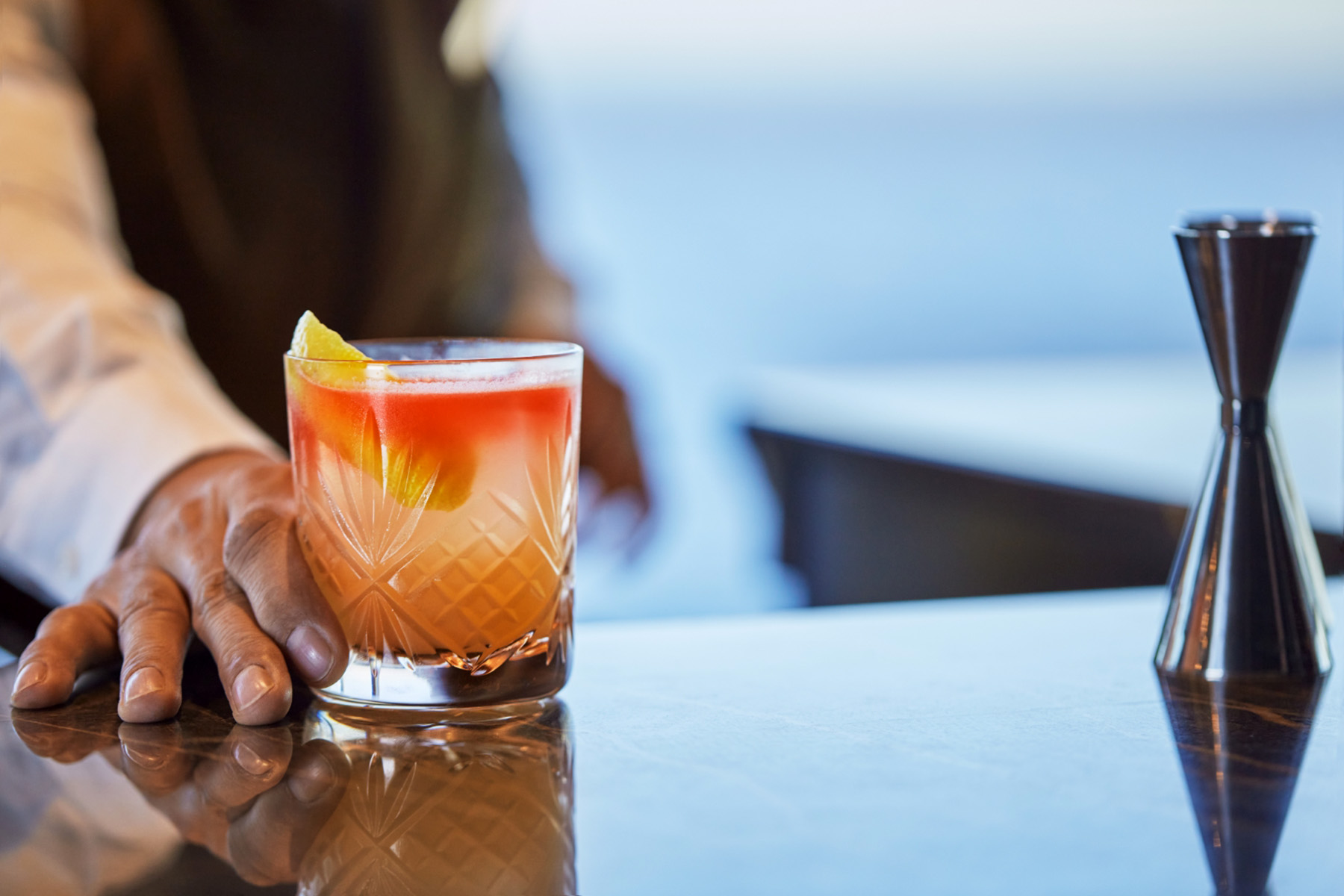 en klar drink med orange färg i baren ombord på kryssningsfartyget Explora Journeys