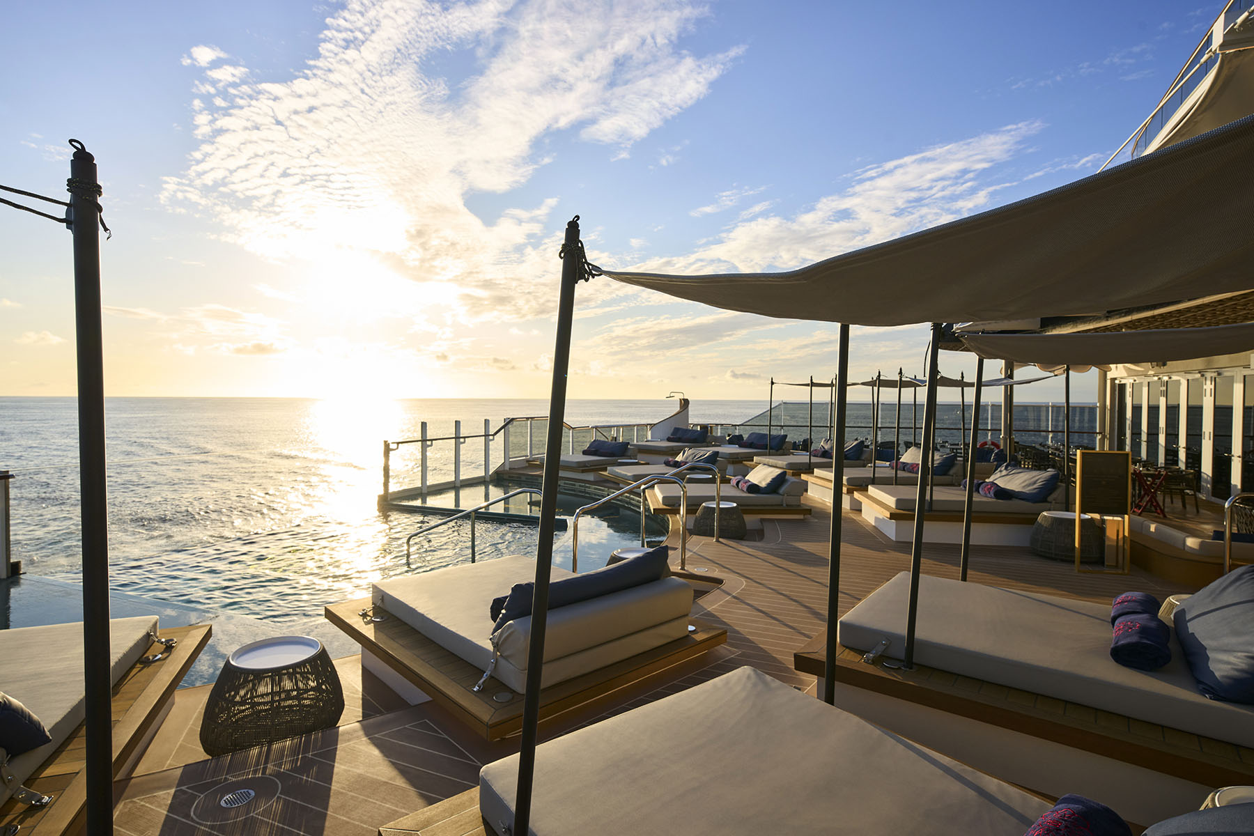 soldäck med parasoller och solsängar i solnedgången ombord på Explora Journeys