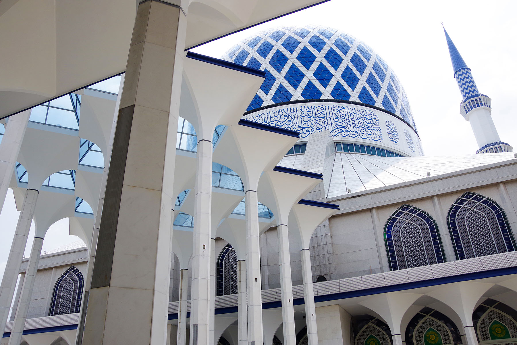 Vackert moskébyggande med blå och vit mosaik, höga minareter och elegant arkitektur, symbol för islamiskt kulturarv och andlig plats. Idealisk för pilgrimsfärd och religiös turism.