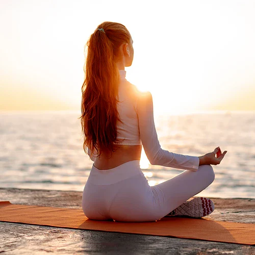 En kvinna gör Yoga på en strand i Tulum i Mexico i soluppgången