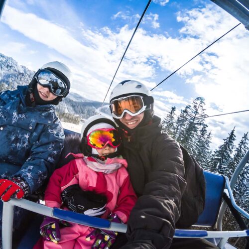 en glad familj som sitter i en lift i Österrikes alper