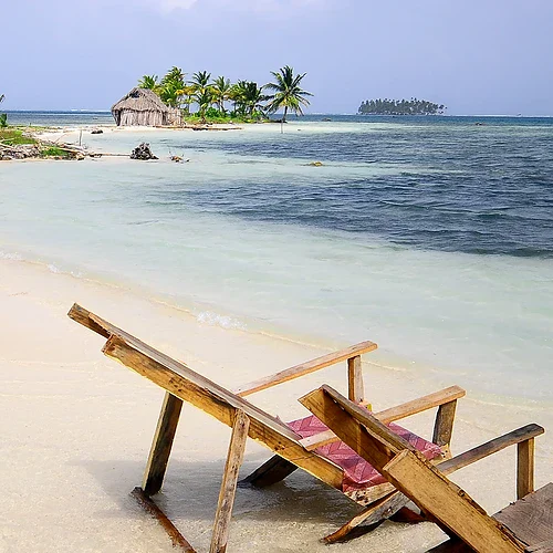 En strand i Panama med bungalow och två strandstolar