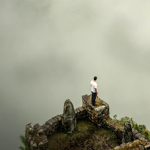 En person på toppen av Machu Picchu som ligger dold i dimma