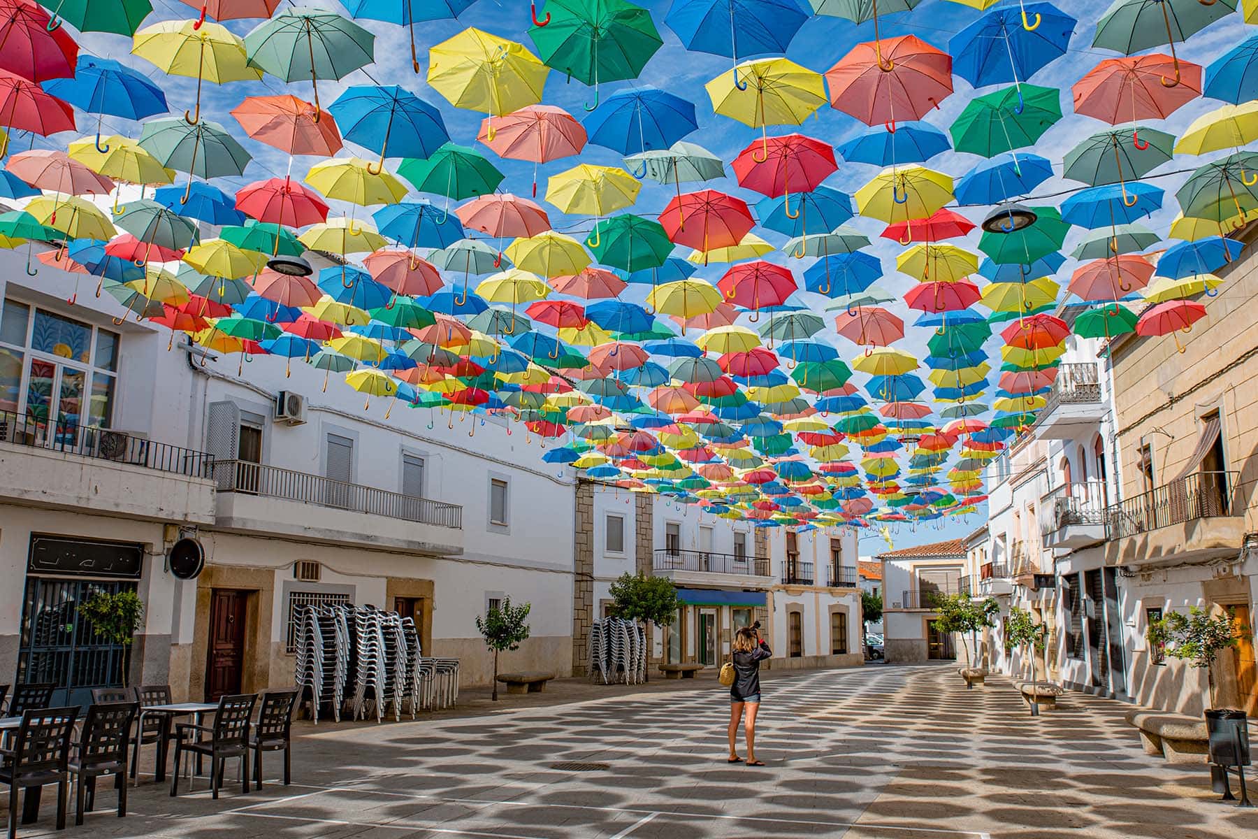 EN gata i Portugal med himmeln  täckt av färgglada paraplyer 