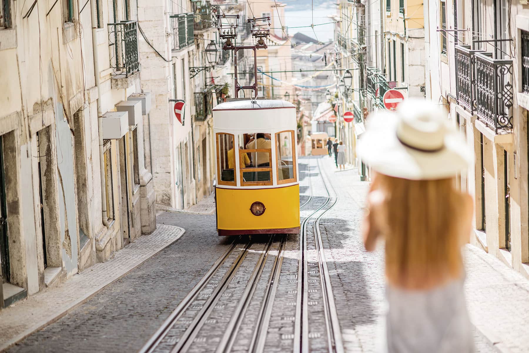 En spårvagn i Portugal på väg upp eller ner en backa med en tjej som har en hatt