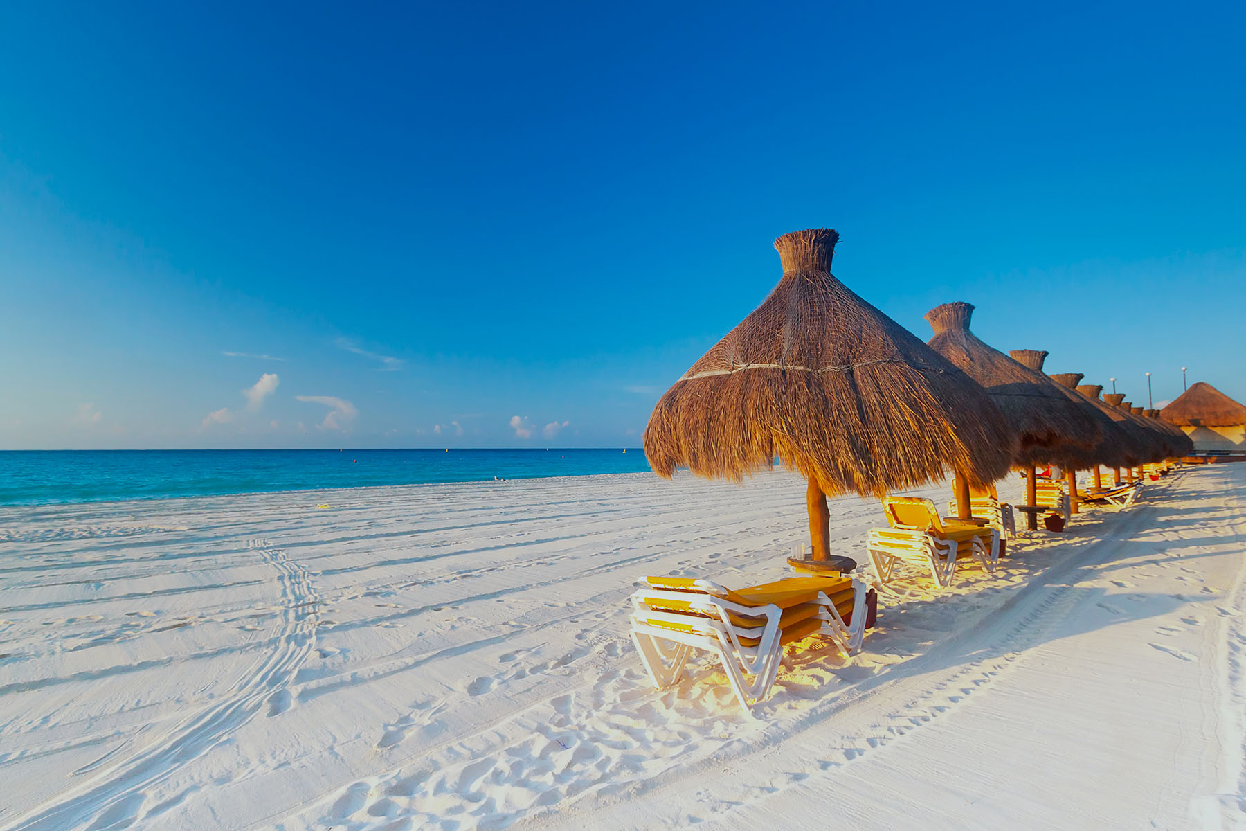 Solparasoller med solsängar på en vit strand i Riviera Maya