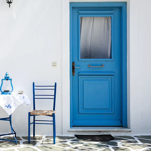 Två blå stolar och ett bord framför en vit vägg på Santorini i Grekland