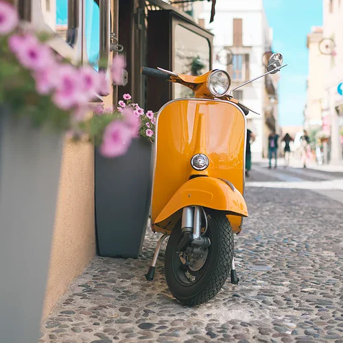 En gul moped i gatorna på Sardinien i Italien