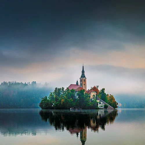 En ö med ett hus och kyrka mitt ute i en insjö i Slovenien