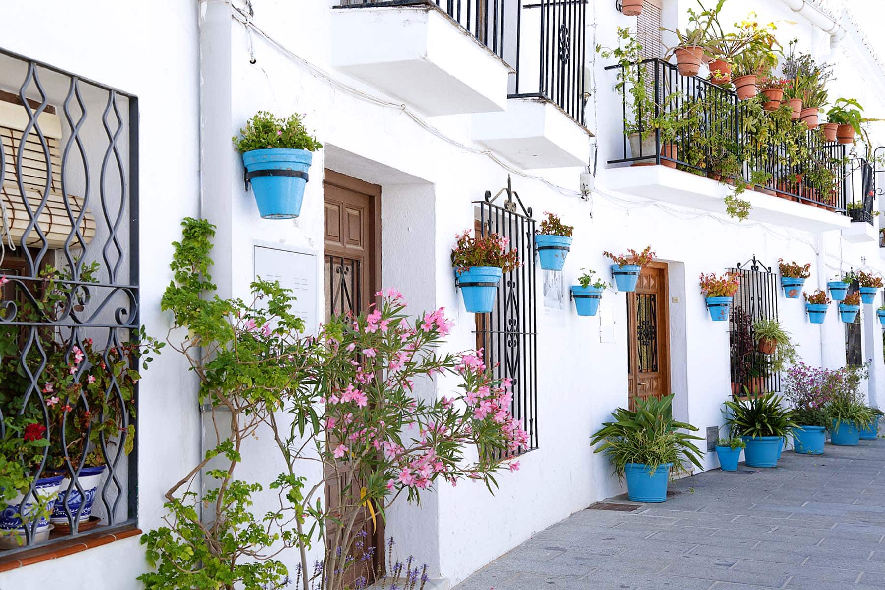 en by i Spanien med vita hus och blå krukor på väggarna och blommor
