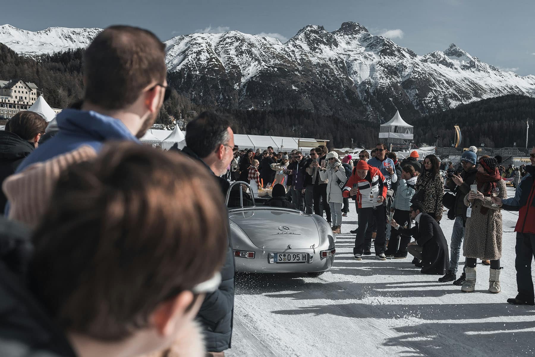 folksamling vid lyxig bil och i snö i St. Moritz