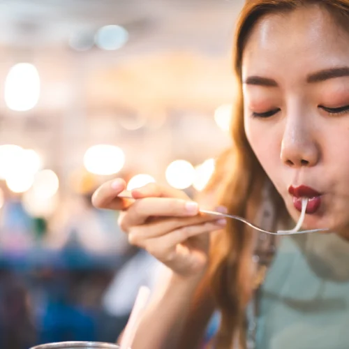 En Thailändsk tjej äter nudlar på en marknad i Bangkok i Thailand