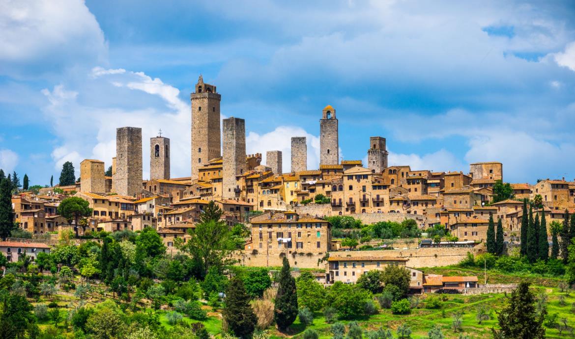 Utsikt över den medeltida staden San Gimignano i Toscana med sina kända torn mot en blå himmel.