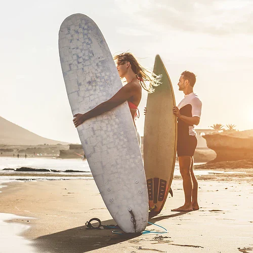 En kvinna och en man med surfbrädor på en strand på Hawaii
